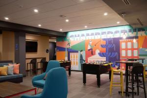 a waiting room with tables and chairs and a large screen at Tru By Hilton Chambersburg in Chambersburg