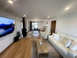 uma sala de estar com um sofá branco e uma televisão em Valentine House em Hadspen