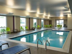 una piscina en una habitación de hotel con mesas y sillas en Home2 Suites By Hilton Fishers Indianapolis Northeast, en Fishers