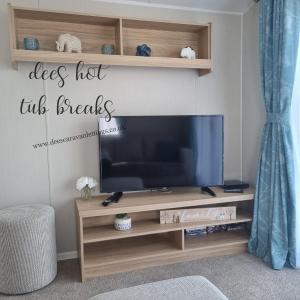 a flat screen tv on a wooden entertainment center at The Grange Mablethorpe Pinewood Retreat 37 in Mablethorpe