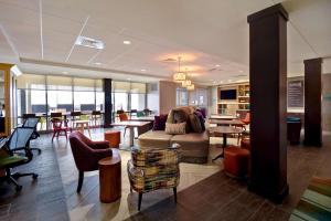 Home2 Suites Wichita Downtown Delano, Ks في ويتشيتا: غرفة معيشة مع أريكة وكراسي وطاولات