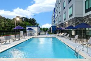 a swimming pool with chairs and umbrellas next to a building at Hampton Inn & Suites Houston East Beltway 8, Tx in Houston