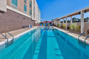 a large swimming pool with blue water in front of a building at Home2 Suites Wilmington in Wilmington