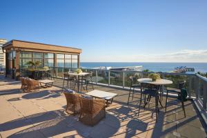 a patio with tables and chairs and the ocean at Home2 Suites By Hilton Pompano Beach Pier, Fl in Pompano Beach