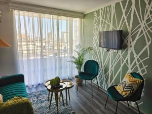 a living room with two chairs and a tv on a wall at Edificio Lynch Centrico in Iquique