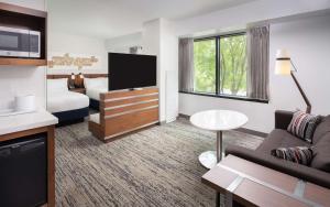 a hotel room with a couch and a tv at Hilton Fairfax, Va in Fairfax