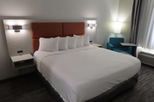 a hotel room with a large bed with white sheets at Best Western Heritage Inn & Suites in Broussard