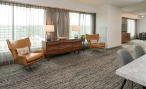 a hotel room with a desk and chairs and windows at Hilton Fairfax, Va in Fairfax