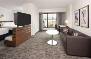 a hotel room with a couch and a tv at Hilton Fairfax, Va in Fairfax
