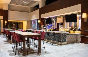 a restaurant with tables and a bar with red chairs at Hilton Fairfax, Va in Fairfax