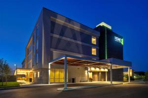 an office building with a lit up sign at night at Home2 Suites By Hilton Grand Rapids South in Byron Center
