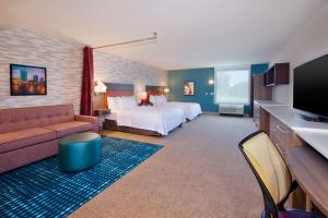 Byron CenterにあるHome2 Suites By Hilton Grand Rapids Southのベッドとソファ付きのホテルルーム