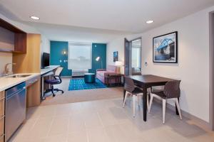 Home2 Suites By Hilton Grand Rapids South في Byron Center: مطبخ وغرفة معيشة مع طاولة وكراسي