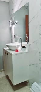 uma casa de banho branca com um lavatório e um espelho em Quarto Luz em Jaraguá do Sul