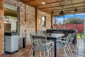 un patio con mesa, sillas y un cubo de basura en Villa in Grand Prairie with pool sauna hot tub and more, en Grand Prairie