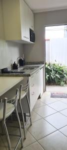 una cocina con 2 sillas, barra y fregadero en Quarto Luz en Jaraguá do Sul