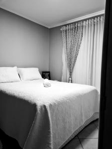 a black and white photo of a bed in a bedroom at Quarto Luz in Jaraguá do Sul