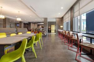 a dining room with tables and chairs and windows at Home2 Suites Galveston, Tx in Galveston