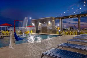 a pool with a slide and a water park at night at Home2 Suites Galveston, Tx in Galveston