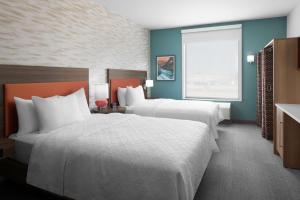 a hotel room with two beds and a window at Home2 Suites By Hilton Hobbs in Hobbs