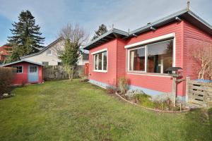 a red house with a yard next to a house at Ferienhaus Aalweg in Niendorf
