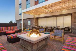 d'une terrasse avec un foyer extérieur, des tables et des chaises. dans l'établissement Home2 Suites By Hilton Leesburg, Va, à Leesburg