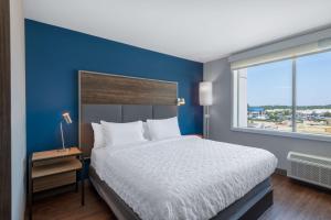 Tru By Hilton Fayetteville Fort Bragg في فايتفيل: غرفة نوم بسرير كبير وجدار ازرق