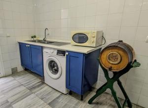eine Küche mit Waschmaschine und Mikrowelle in der Unterkunft Adosada en El Puerto Santa María in El Puerto de Santa María