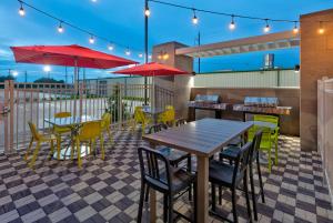 un patio con mesas, sillas y sombrillas rojas en Home2 Suites By Hilton El Campo, en El Campo
