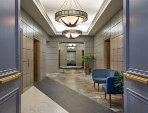 an office lobby with a hallway with blue chairs and a chandelier at The Chifley Houston, Tapestry Collection by Hilton in Houston