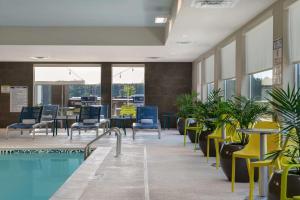 a swimming pool with chairs and tables in a building at Home2 Suites By Hilton Fayetteville North in Fayetteville