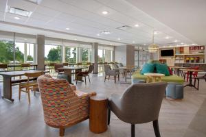 a waiting room with tables and chairs and tablesktop at Home2 Suites By Hilton Grand Rapids Airport in Kentwood