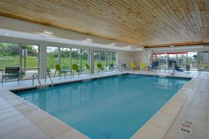 uma grande piscina com cadeiras e mesas num edifício em Home2 Suites By Hilton Grand Rapids Airport em Kentwood