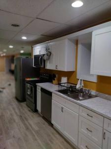 uma cozinha com armários brancos, um lavatório e um frigorífico em Unique Center Of Downtown Elmira em Elmira