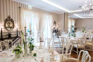 une salle à manger avec des tables et des chaises blanches dans l'établissement Schlosshotel Münchhausen, à Aerzen