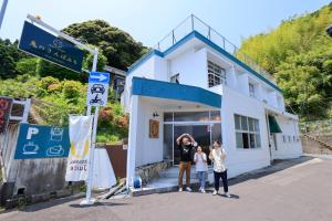 Eine Frau und zwei Kinder stehen vor einem Gebäude in der Unterkunft Oninosanpomichi in Kumano