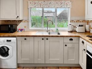 a kitchen with white cabinets and a sink and a window at The Cottage in Fressingfield