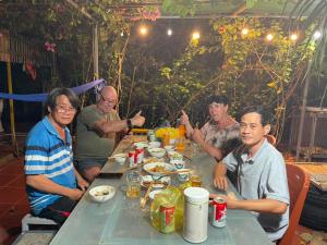 un grupo de personas sentadas en una mesa comiendo en Đức Lưu Quang Hotel Bình Thuận, en Tuy Phong