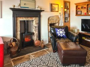 a living room with a fireplace and a chair at Hafod in Lower Boscaswell