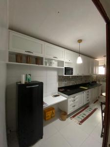 a kitchen with white cabinets and a black refrigerator at Casa Zohra in Itaparica