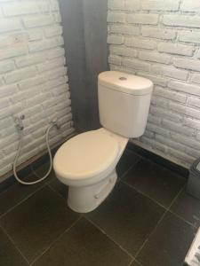 a white toilet in a bathroom with a hose at Bulian Homestay in Kubutambahan