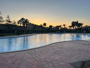 a large swimming pool with a sunset in the background at شالية ارضى مميز فى السخنة in Ain Sokhna