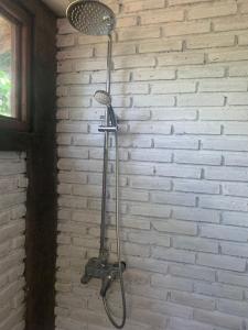 una ducha de metal en una habitación con una pared de ladrillo en Bulian Homestay, en Kubutambahan