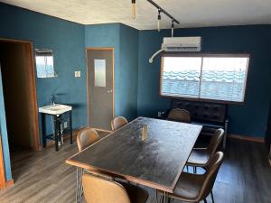 una mesa y sillas en una habitación con una pared azul en GuestHouse紫雲, en Toyohama