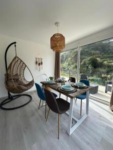 a dining room with a table and chairs and a large window at The Green Valley House in São Vicente
