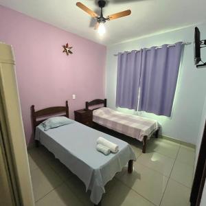 a bedroom with two beds and a ceiling fan at Hotel Mirante in Inhaúma