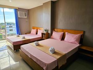 two beds in a hotel room with pink pillows at Jaelle Residences Hotel - Downtown in Lucena