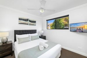 a bedroom with a white bed and a window at Tomaree Road 16 in Shoal Bay