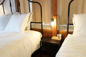 a bedroom with two beds and a table with a lamp at YKHouse 尾道から車で10分 駐車場完備 in Mihara