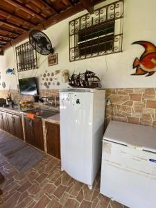 a kitchen with a white refrigerator and a sink at Sítio Curumim - Zohra in Itaparica